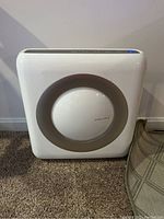 Front view of Coway air purifier showing circular vent with grey ring and logo.