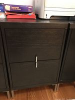 Front view of two drawer dark wood file cabinet showing scratches and metal handles.