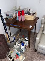 Full view of wood folding table holding various items including baskets, red cups, and boxes, with containers below it.
