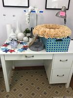 Desk with decorative items including white vases, faux flowers in basket, star decorations, marble balls, small plant, and wreaths.