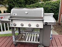 Front view of grill with lid closed, shows four burners and control panel.
