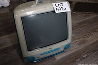 Front and left side view showing the CRT monitor with beige front and teal accents, with some age yellowing and an Apple logo.
