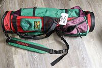 Side view of multicolor retro golf club bag with shoulder strap and zippered pockets, showing wear and tear.