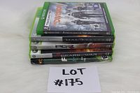Five Xbox video game cases stacked, showing titles and platform labels