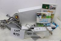 Photo of entire lot including Nintendo Wii console, game cases, controllers, and cables.