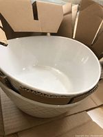 Top view of white porcelain serving bowls stacked inside cardboard packaging