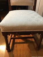 Close-up of the upholstered seat and lower carved wood frame of the antique mahogany chair.