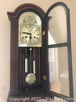Full front view of the wooden Tempus Fugit wall clock with glass door open showing clock face and pendulum weights.
