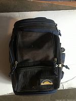 View of the closed California Innovations insulated bike cooler bag showing front zippered compartments with mesh pocket and logo.