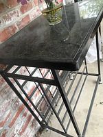 Side angled view showing granite top and iron frame with wine bottle holders