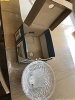 Open box with clear crystal bowl inside on a wooden table.