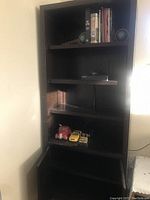Full view of the Crate Barrel dark solid wood bookshelf showing multiple shelves with books and decorative items.