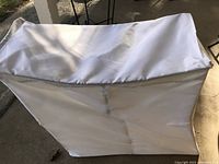 Top and side views of white fabric laundry hamper bin with fitted lid, showing structure and condition.