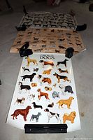 Three large animal posters including dogs, cats, and horses laid flat on a floor held with clips in corners.
