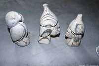 Front and side view of the three petrified wood carvings showing details and textures.