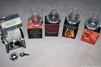 Photo showing 4 whiskey glasses on boxes with a stainless steel brandy warmer set on the side, all items new except the brandy warmer box is damaged.