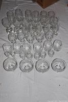 Set of 37 matching glasses of various sizes arranged on a white cloth, includes small to large glasses and 4 round fruit cups at the front.