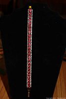Front view of tennis bracelet with pink rhinestones and clear crystals on black display stand