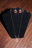 Entire necklace and earrings set displayed on black necklace stand showing full length and matching design.