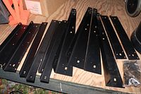 Black powder-coated steel legs and brackets for tool table stand laid out on plywood surface