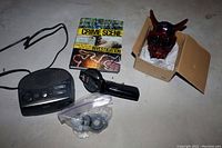 Full view of the lot including the Philips radio, Crime Scene Investigation book, red horned mask in box, and label maker with extra rolls in plastic bag