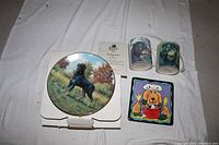 Top view photo showing the Rottweiler plate in its box, two Rottweiler mugs, and the colorful Dogzilia hot plate.