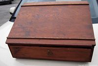 View of the sloped wooden tabletop showing the wood grain and wooden ledges at the top and bottom edges.