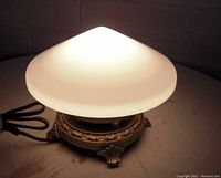 Lit view of the glass mushroom table lamp showing soft white light and brass base details.