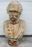 Front view of large plaster bust showing facial features, military attire, and surface wear.