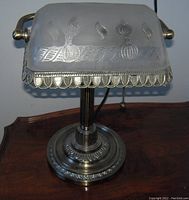 Frosted glass banker's table lamp showing etched pattern on the shade and metal base design.