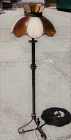 Full view of the metal floor lamp with stained glass shade outdoors showing height and design.