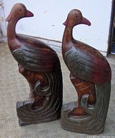 Pair of large carved wood bird sculptures showing side and front details of wings, beaks, and bases.
