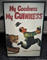 Framed vintage beer poster titled "My Goodness My Guinness" showing man chased by a dog holding Guinness beer items, in black frame