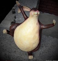 Front angled view of resin dancing rabbit statue on concrete step showing full body from front with arms raised and one foot in air.