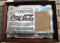 Front view of rectangular wood framed mirror with Coca-Cola advertising text and graphics.
