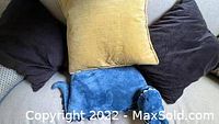 Four assorted microfiber pillows arranged on a surface showing the yellow square pillow, two dark brown pillows, and the blue dinosaur pillow