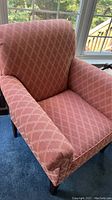 Front and side view of an upholstered club chair in dusty rose pink with diamond lattice pattern, showing the fabric and wooden legs.