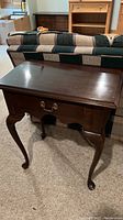 Ethan Allen dark wood lamp table in front of a couch, showing front and side profile, including Queen Anne style cabriole legs.