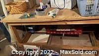 Photo showing top and front view of the workbench with some tools and supplies placed on top and in boxes underneath.