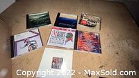 Photo showing the seven music CDs arranged on a surface, featuring Mozart, Journey, Willie Nelson, and other artists.