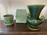 Three Shawnee pottery items displayed on a wooden surface: large vase, planter with saucer, and letter holder.