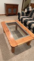 Side angle photo of the solid pine coffee table showing the rounded legs and wood grain around the glass inset.