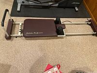 Top-down photo of the full reformer showing padded platform with 'Pilates Performer' text, footbar and frame.