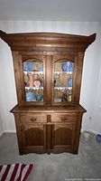 Front view of vintage solid oak china hutch showing upper glass doors and lower cabinets
