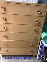 Front view showing six drawers with round wooden handles and light birch finish.