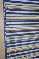 Close up of black stains on the blue striped rug corner edge.