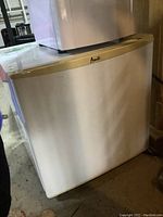 Front and side view of the Avanti small square bar fridge showing white exterior and yellowed trim.