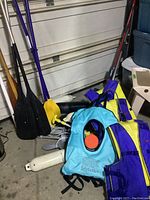 Image showing mix of wooden and plastic paddles alongside boat fenders and life jackets