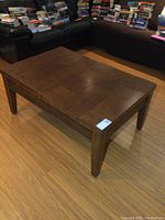 Angle view of the closed wooden coffee table with block pattern top surface, showing minor wear.