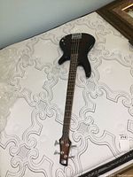 Full front view of electric bass guitar on mattress
